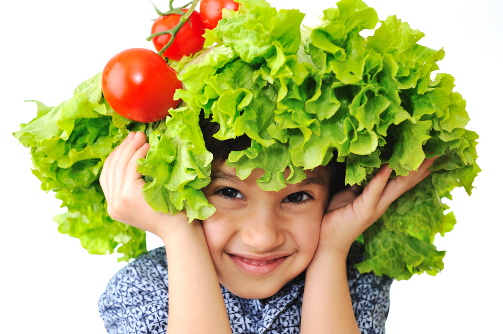 Portrait of a smiling child with lettuce and tomatoes on his head